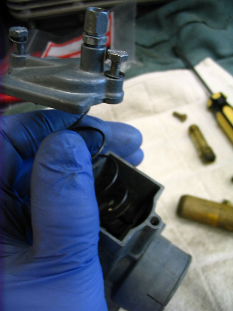 Now place the carburetor top complete with spring onto the top of the carburetor. Note that the cable adjuster is positioned nearest the intake manifold, not the air filter.