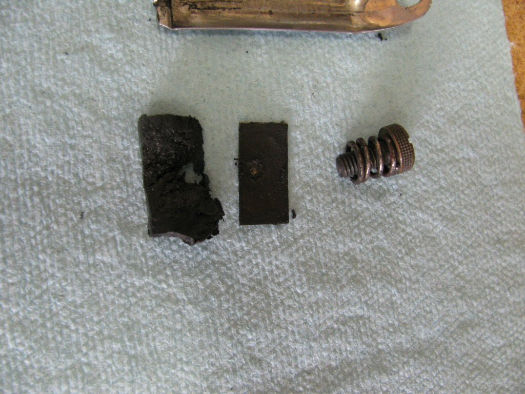 Rubber friction material (left), thin metal backing plate for the friction material (so the screw does not push through the rubber friction material), friction screw and spring.