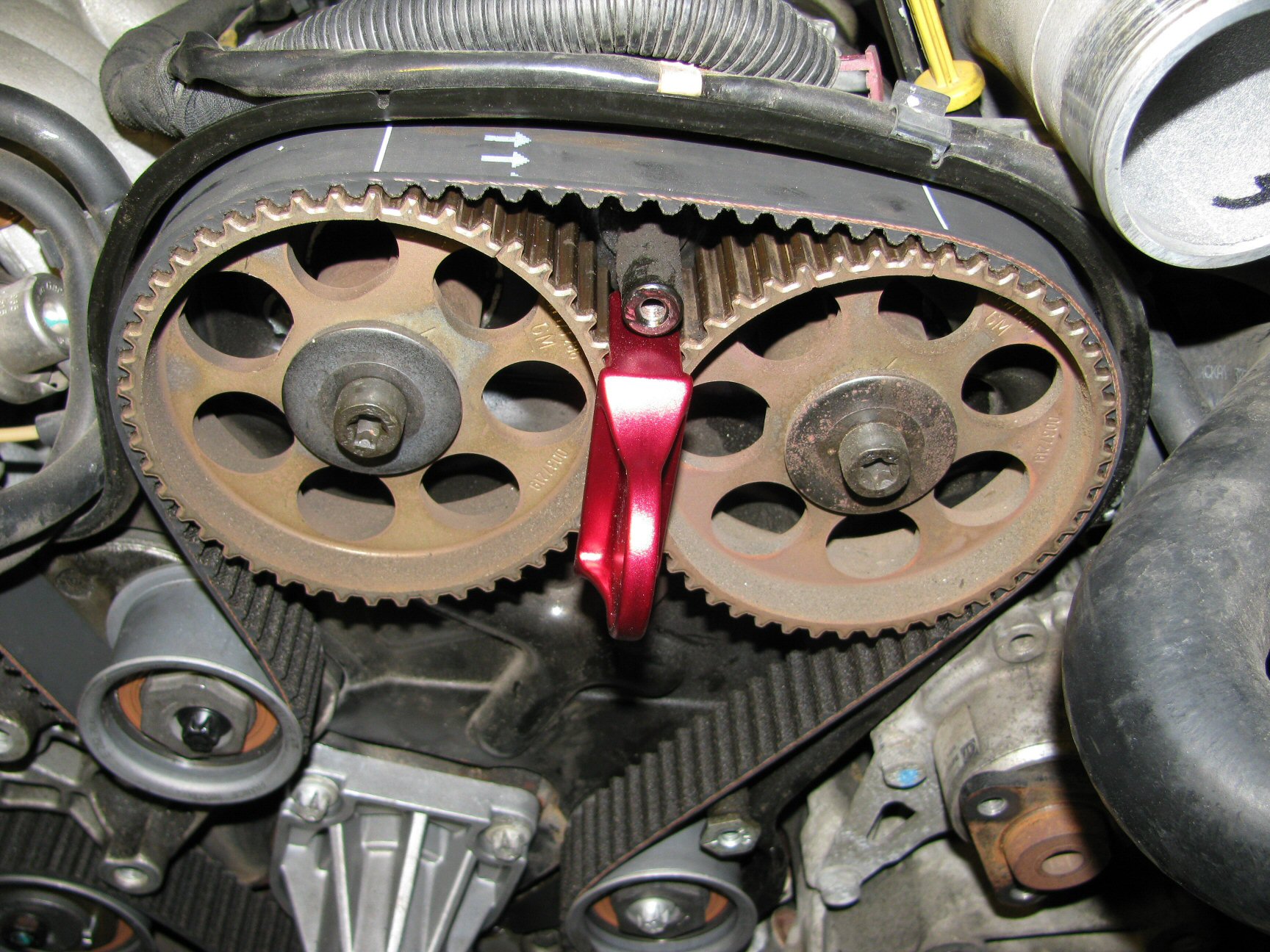 New belt positioned on camshaft pulleys 3 and 4. Note the white lines on the belt. Note also the arrows indicating the direction of belt rotation.