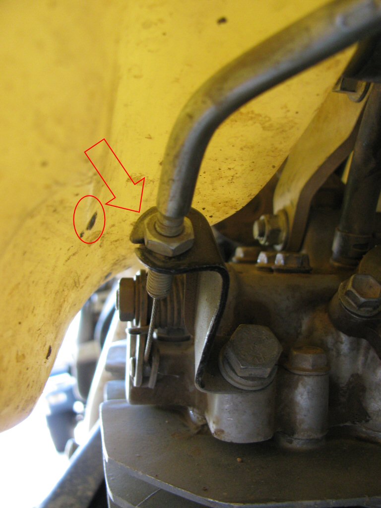 Clarke tank on my 1993 Suzuki DR350. The circle indicates where the tank was rubbing on the bracket for the decompression lever. The arrow shows where I used my bench grinder to radius the previously 90° corner...providing additional clearance.