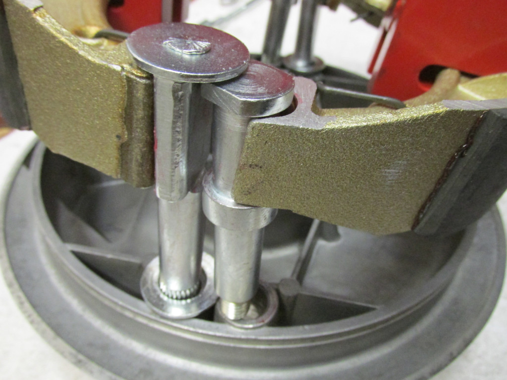 The pivots fit as shown. Note the large flat washers under the rotating pivot. Apply a light coating of grease both to the portion that fits between the brake shoes AND the shaft that fits through the rear brake plate.