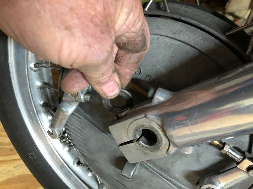 Before you slide the axle all the way through, don't forget to insert the washer / spacer between the outside of the backing plate and the inside of the fork leg. You probably didn't notice it fall out when you withdrew the axle. It will have rolled away under the whisky cabinet.