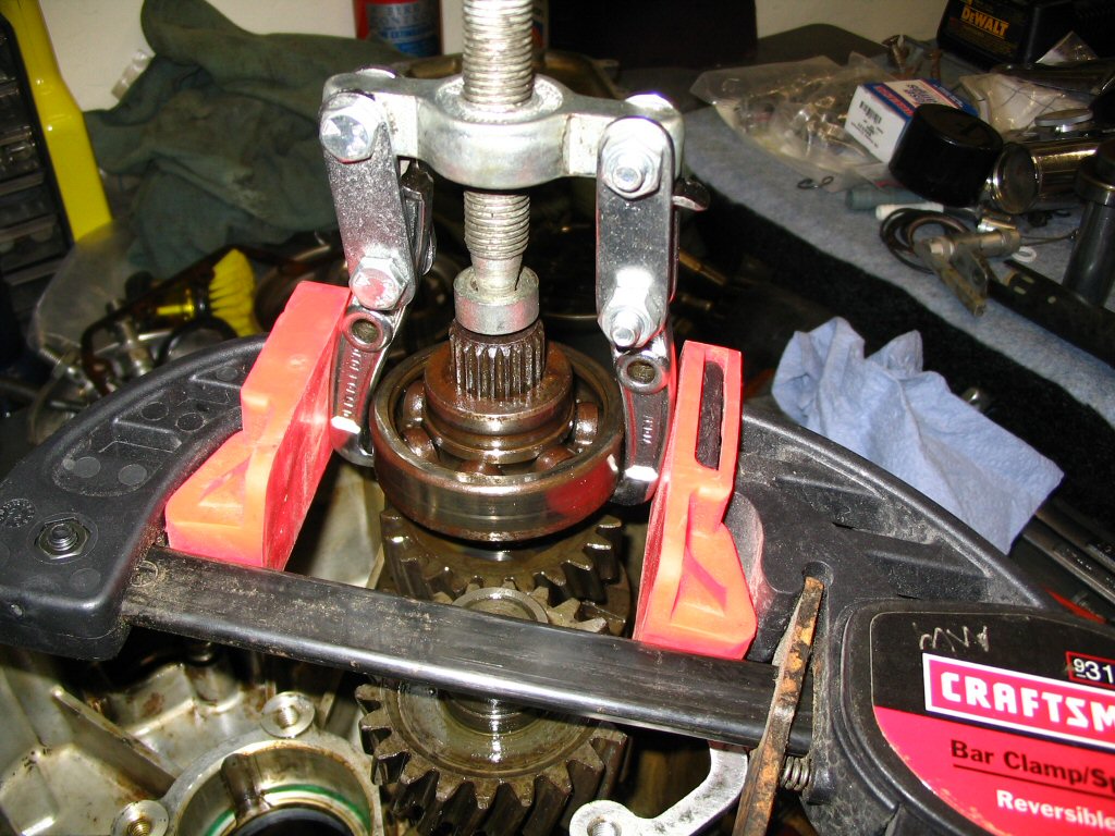 This is the puller arrangement I devised to get the rear bearing and the spacer that the seal runs on off of the output shaft. I chose to pull them off as a unit because (a) the spacer that the seal runs on was stuck in place and (b) I did not want to risk damaging the sealing surface of the spacer that the seal runs on. The clamp was very useful to keep the fingers of the puller lodged under the bearing.