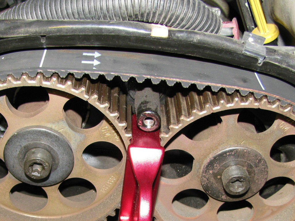 New belt positioned on camshaft pulleys 3 and 4. Note the white lines on the belt. Note also the arrows indicating the direction of belt rotation.